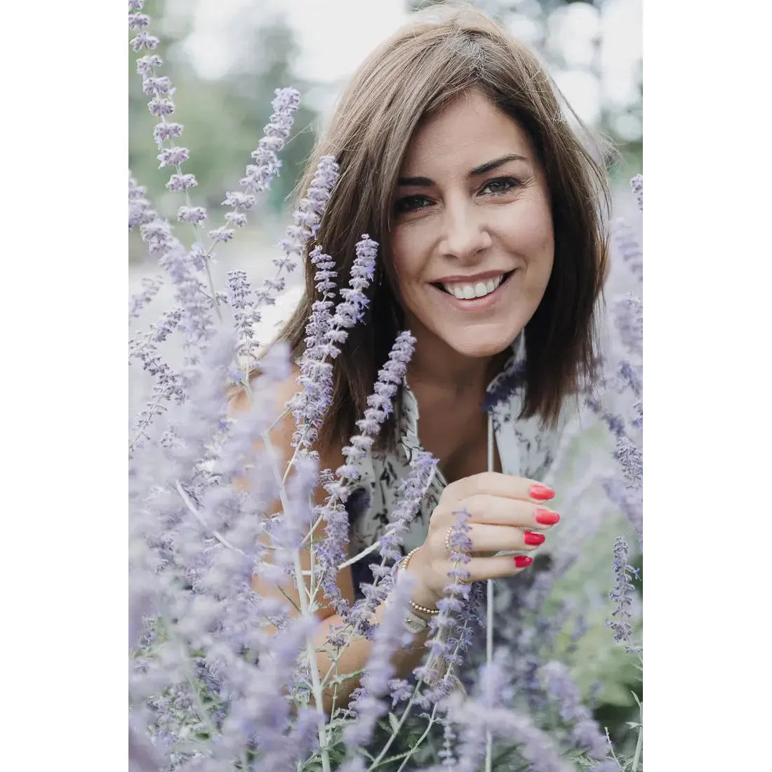 Woman smiling amid lavender flowers, showcasing a joyful connection with nature and beauty.