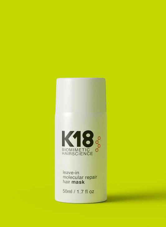 K18 Biomimetic Hairscience leave-in molecular repair hair mask in a white bottle on a vibrant green background.