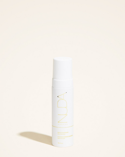Sunless Tan Remover mousse bottle, featuring a sleek design with white and yellow branding on a neutral background.
