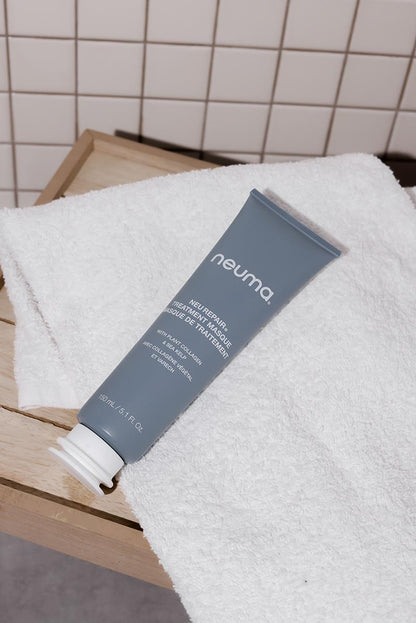 Neuma Repair Treatment Masque on a white towel, perfect for restoring damaged hair and enhancing shine.