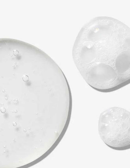 Close-up of clear gel droplets and bubbles, showcasing the hydrating formula of Redken All Soft Mega Curls Shampoo.