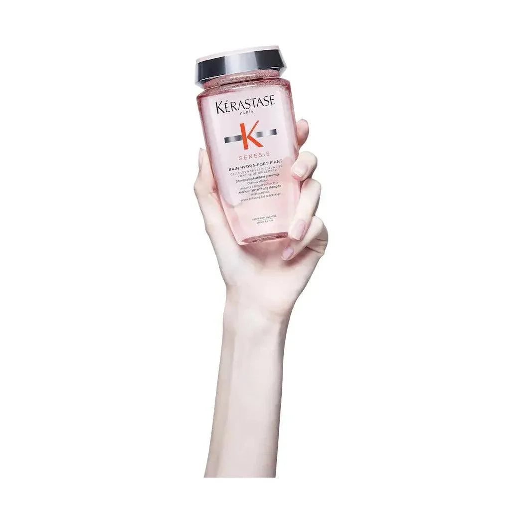 Hand holding a bottle of Kérastase Genesis hair serum for hair strengthening and anti-hair fall treatment.