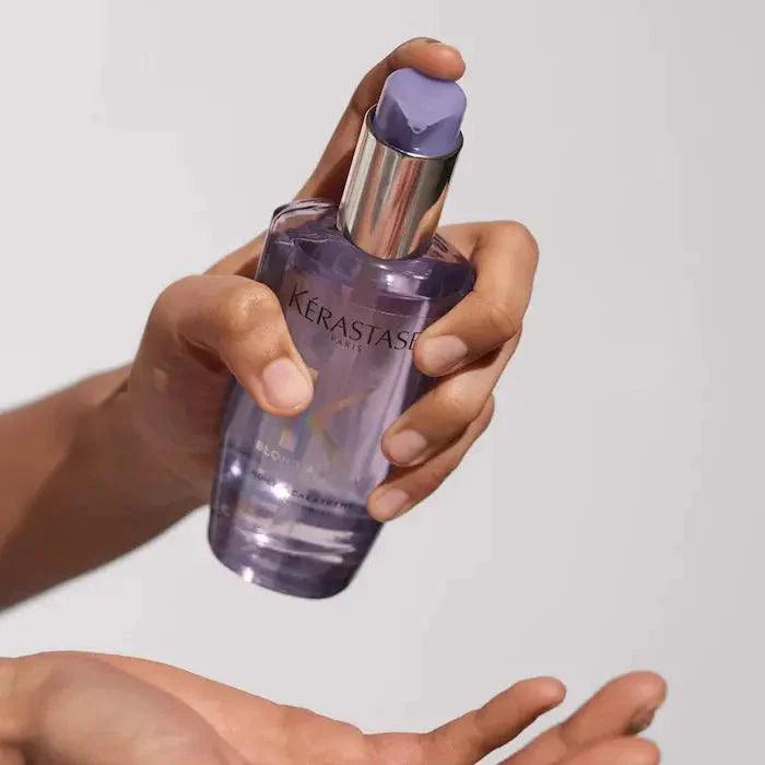 Person holding a bottle of Kérastase Blond Absolu hair serum for blonde hair care