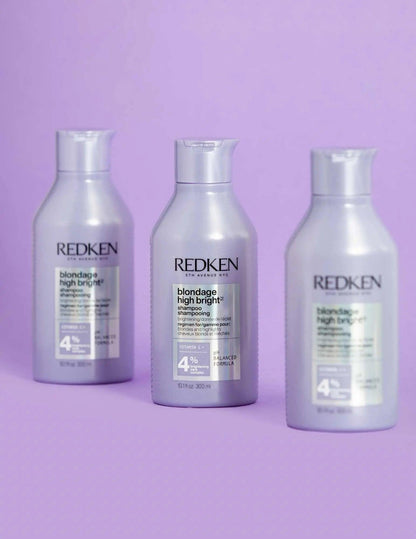 Three bottles of Redken Blondage High Bright Shampoo against a purple background, ideal for vibrant blonde hair.