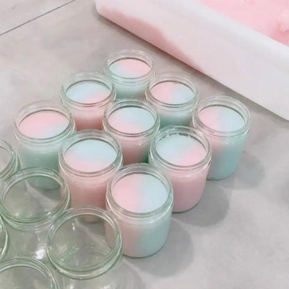Various jars of colorful cotton candy-scented body scrub with pink and blue layers, ready for use.