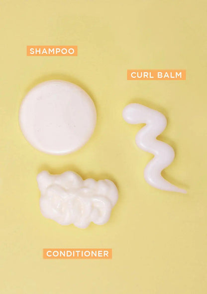 BOUNCE.ME Curl Glitz Kit featuring shampoo, conditioner, and curl balm displayed on a yellow background.