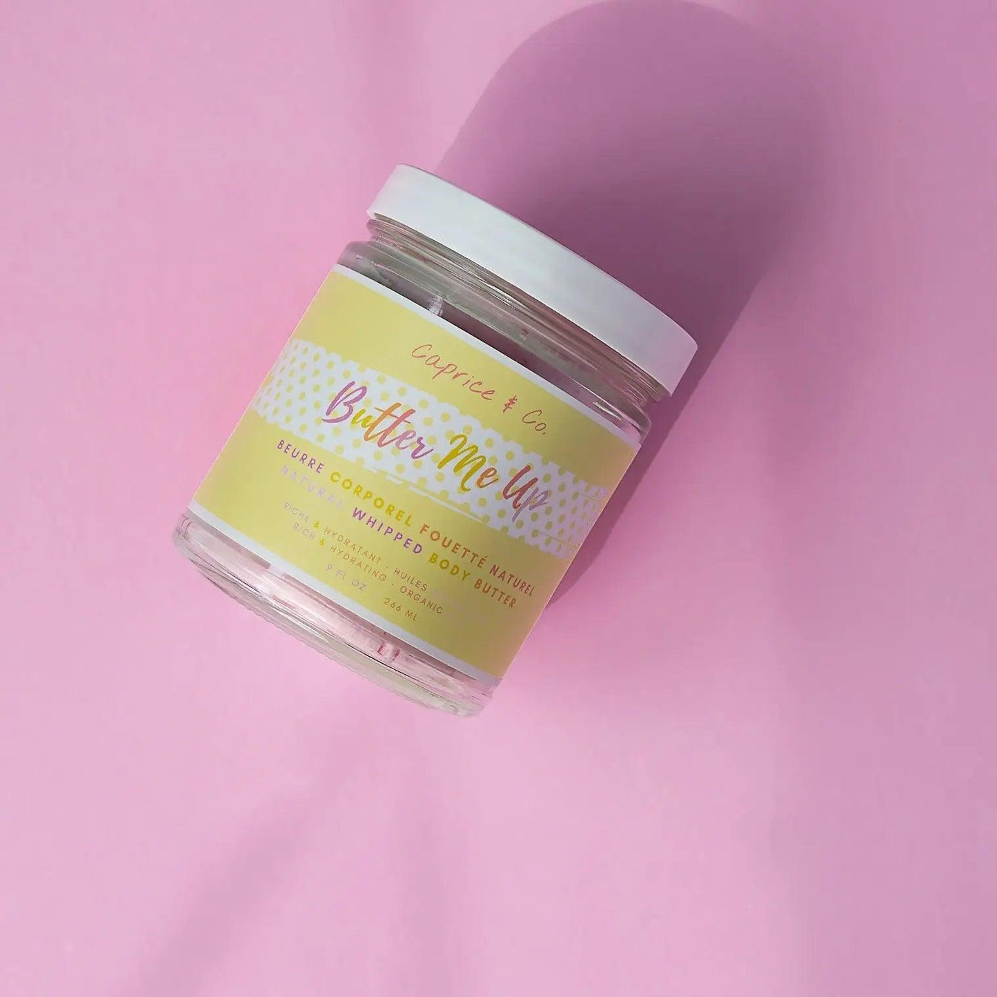 Butter Me Up whipped body butter jar with Fruit Loops scent on pink background, showcasing its vibrant label and design.