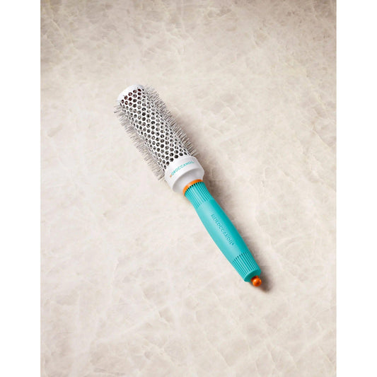Ionic ceramic round brush with retractable styling clip for faster drying time, featuring a turquoise handle and ventilation holes.