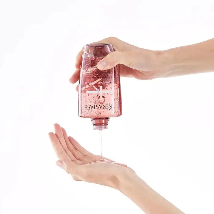 Pouring Kerastase hair care product from bottle into hand for hair treatment.