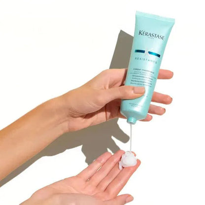 Person squeezing Kerastase Resistance hair treatment into hand.