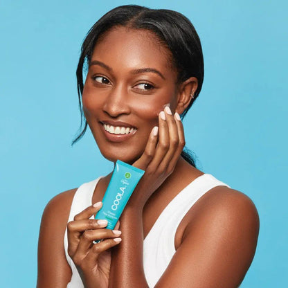 Smiling woman holding Classic Face Organic Sunscreen Lotion SPF 30 with a blue background, showcasing radiant skin protection.