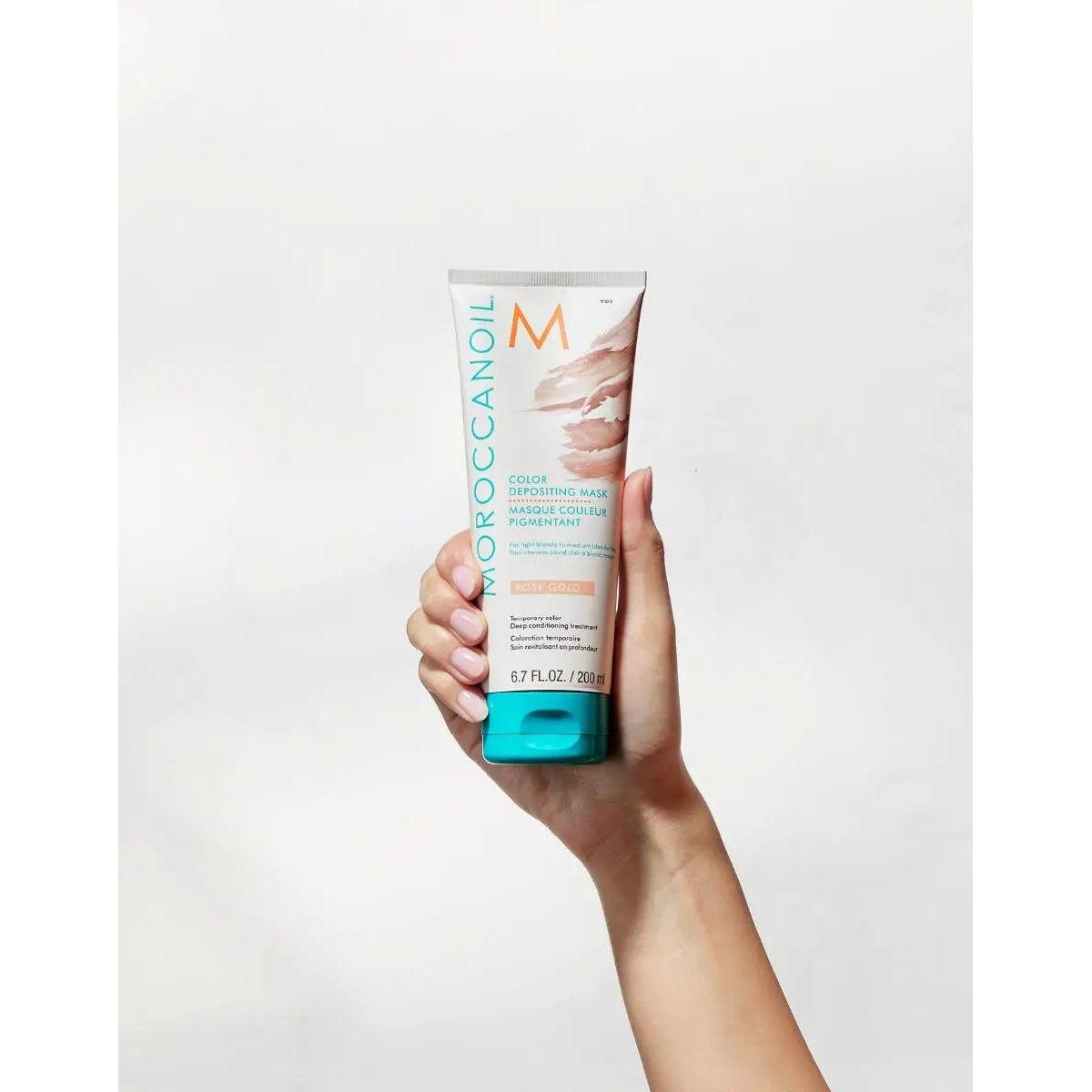 Moroccanoil Color Depositing Mask in a hand, promoting hair rejuvenation and vibrant color enhancement.