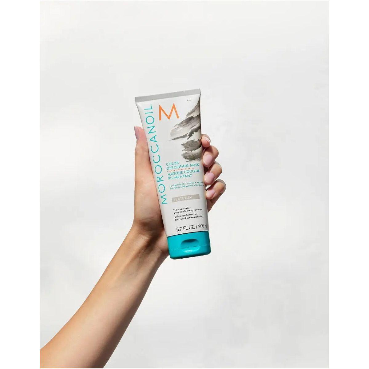 Moroccanoil Color Depositing Mask held in hand, showcasing hair rejuvenation and color enhancement benefits.