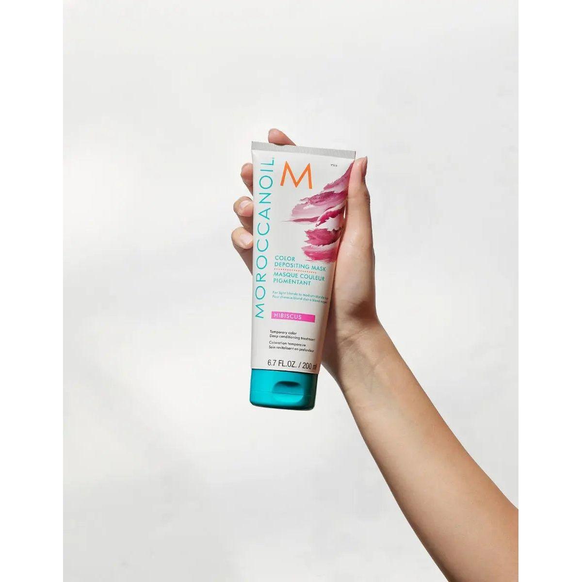 Moroccanoil Color Depositing Mask in hand, revitalizing hair color and enhancing shine.