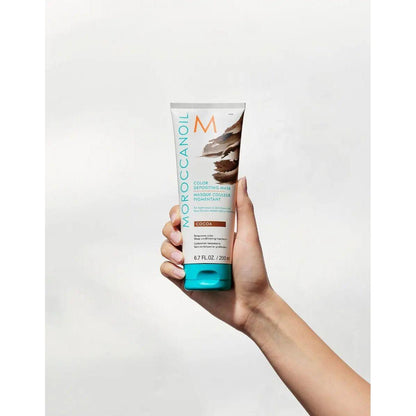 Moroccanoil Color Depositing Mask in hand, rejuvenates hair color and enhances tone for vibrant, healthy hair.