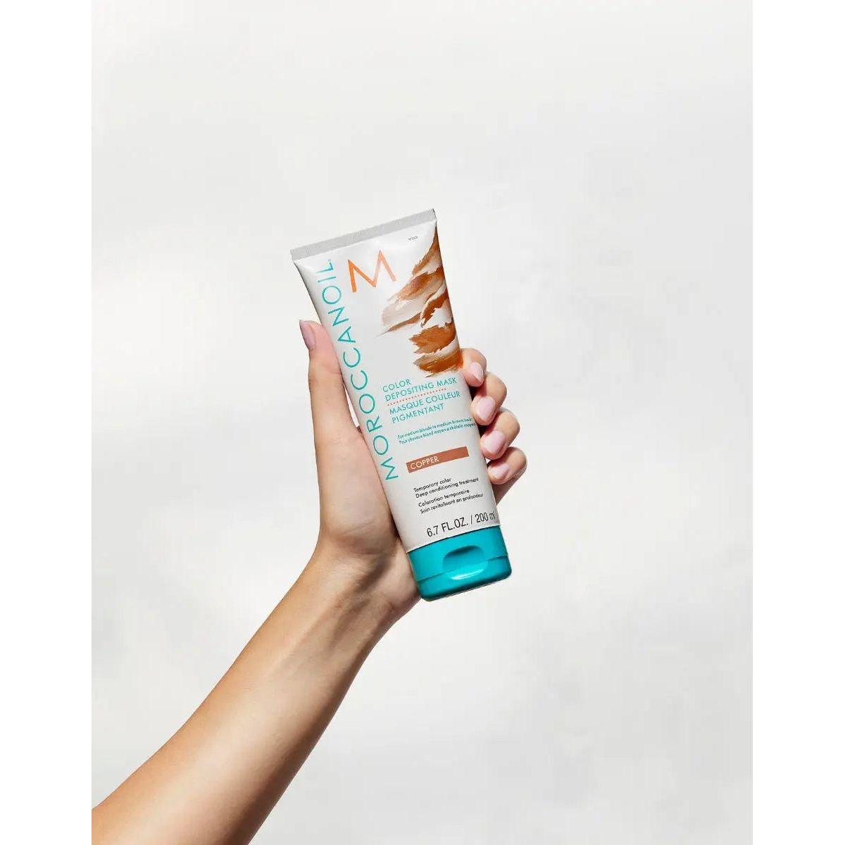 Moroccanoil Color Depositing Mask held in hand, perfect for refreshing and enhancing hair color.