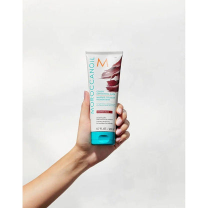 Moroccanoil Color Depositing Mask held in hand, rejuvenating hair color and enhancing softness.