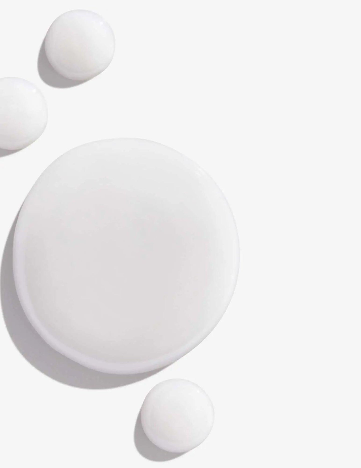 White creamy texture of Redken Color Extend Shampoo with droplets on a clean background.