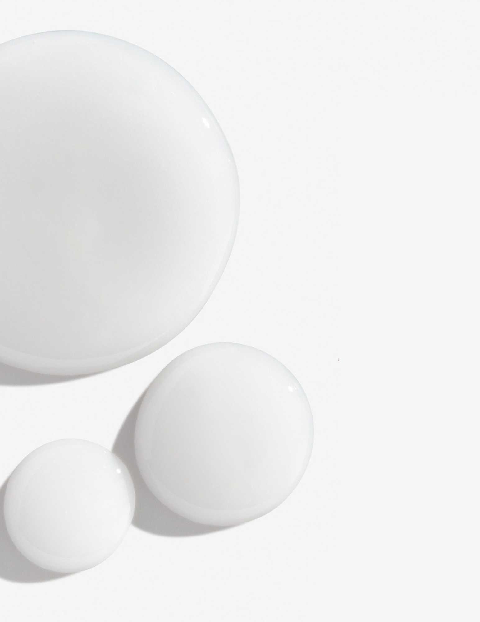 Drops of creamy white shampoo on a smooth surface, ideal for color-treated hair care.