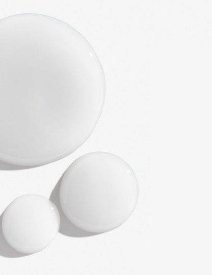 Drops of creamy white shampoo on a smooth surface, ideal for color-treated hair care.
