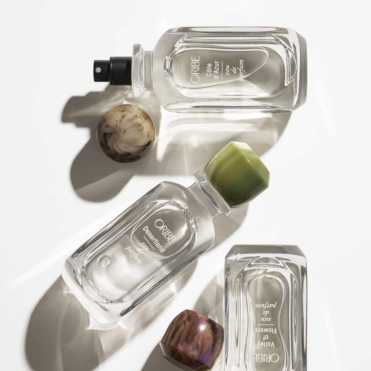 Oribe glass perfume bottles with luxurious caps, displayed elegantly on a white surface