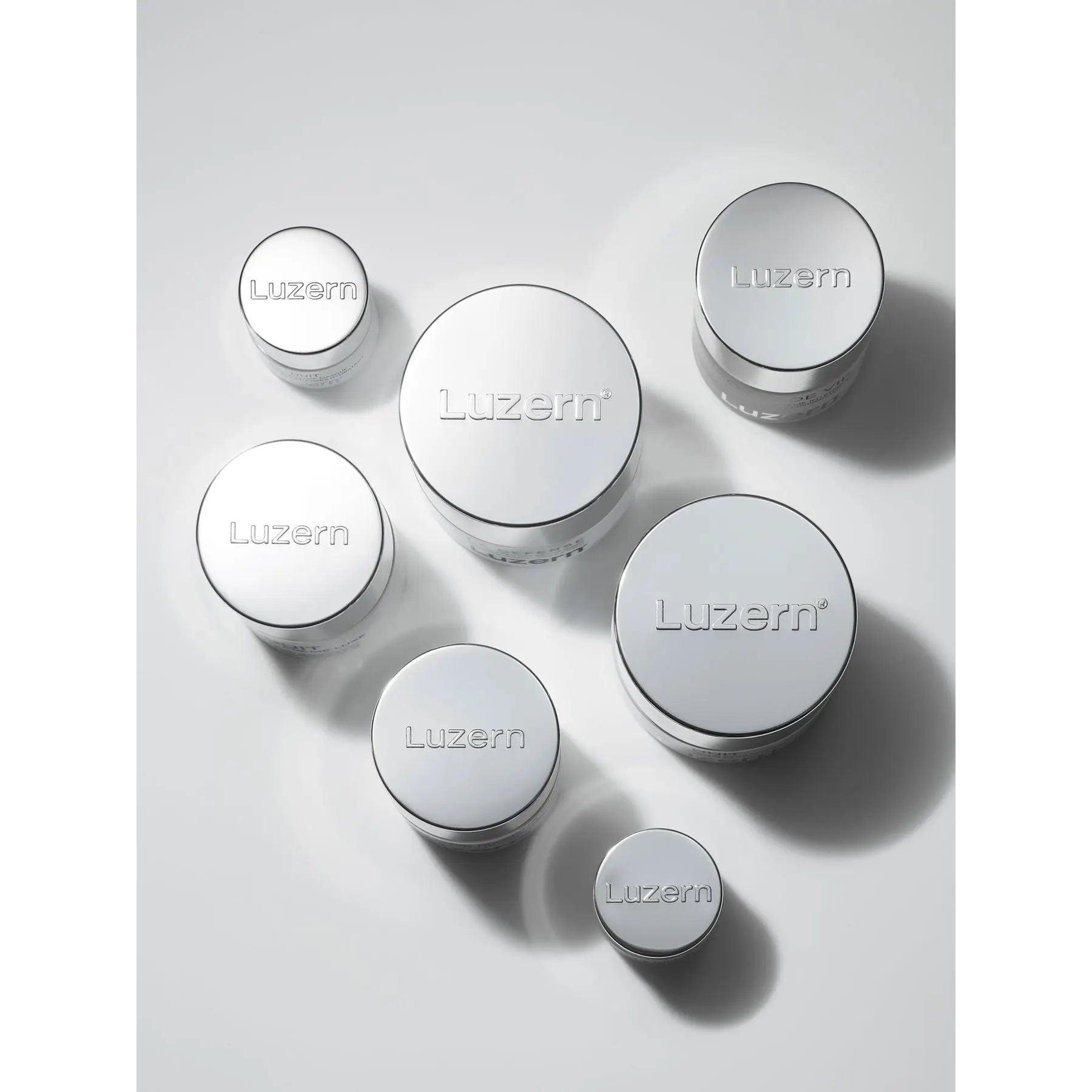 Various sizes of Luzern skincare cream jars with sleek silver packaging displayed on a light background.