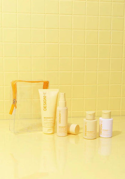 Curl Discovery Kit featuring BOUNCE.ME shampoo, conditioner, curl balm, spray gel, and a clear pouch against a yellow background.