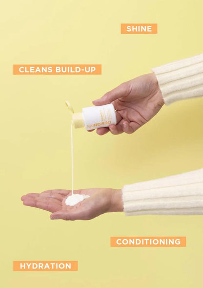 Hand pouring curl product into palm, showcasing shine, hydration, and conditioning benefits on yellow background.