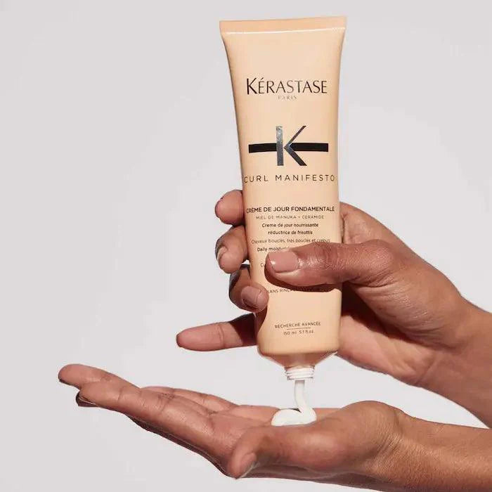 Kérastase Curl Manifesto Crème De Jour Fondamentale hair cream being applied to hand for hydration and curl definition.