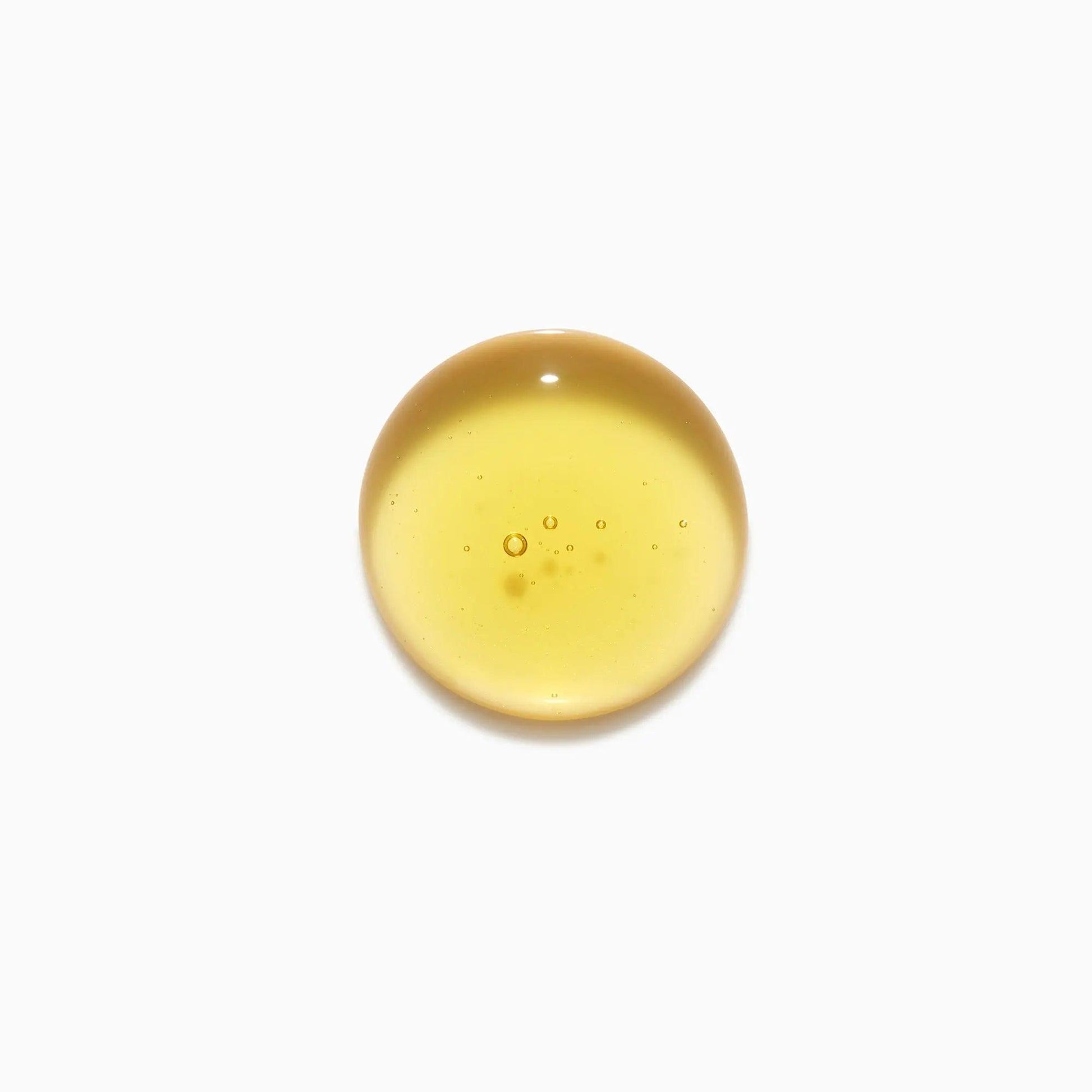 Clear drop of yellow essential oil for skincare on white background