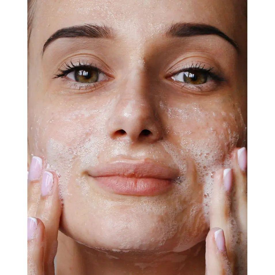 Woman using face cleansing foam to gently cleanse her skin, showcasing a fresh and radiant complexion.