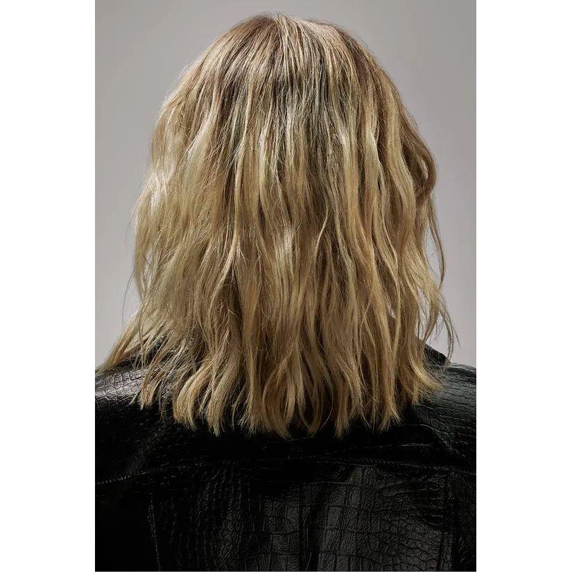 Back view of woman with messy blonde shoulder-length hairstyle in black leather jacket