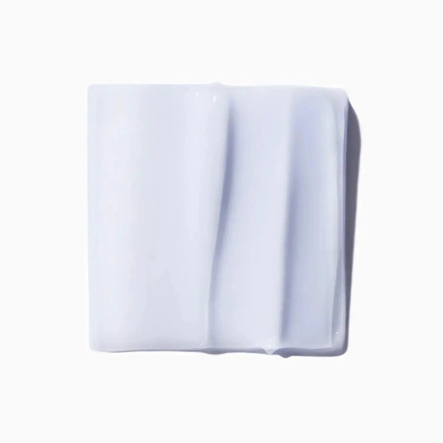 Close-up of white skincare cream texture on a square surface, illustrating smooth and rich consistency.