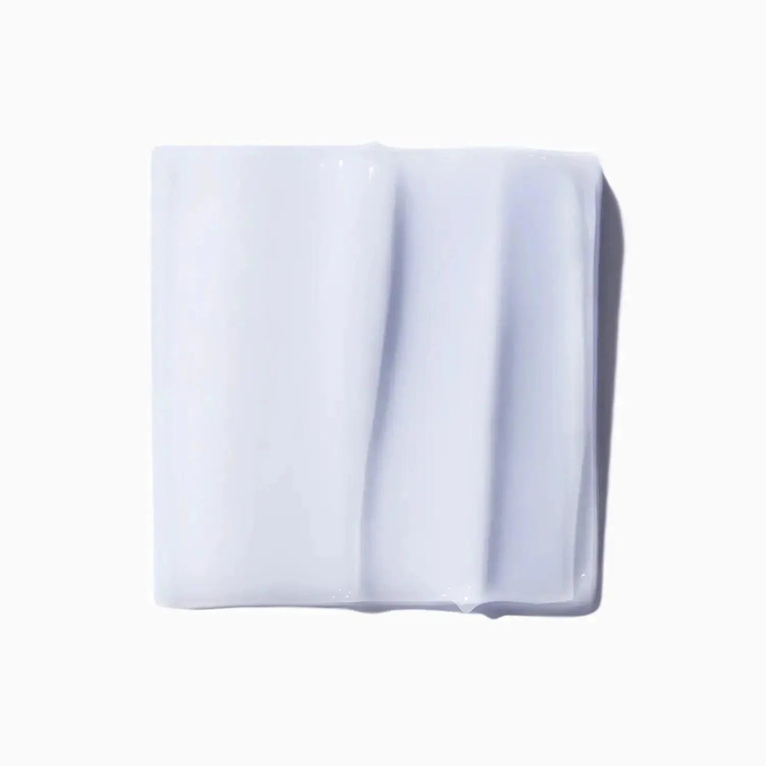 Close-up of white skincare cream texture on a square surface, illustrating smooth and rich consistency.