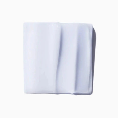 Close-up of white skincare cream texture on a square surface, illustrating smooth and rich consistency.