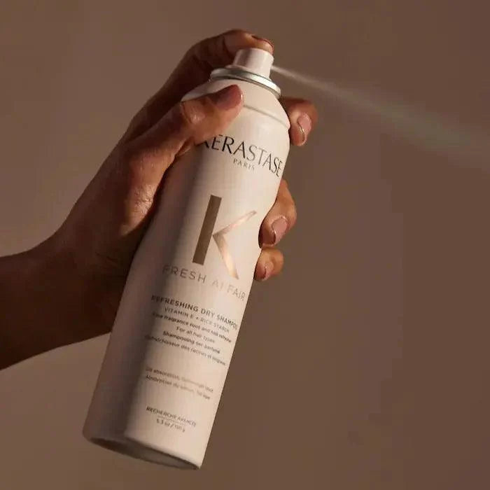 Hand holding Kérastase Paris dry shampoo spray bottle for hair freshness and volume