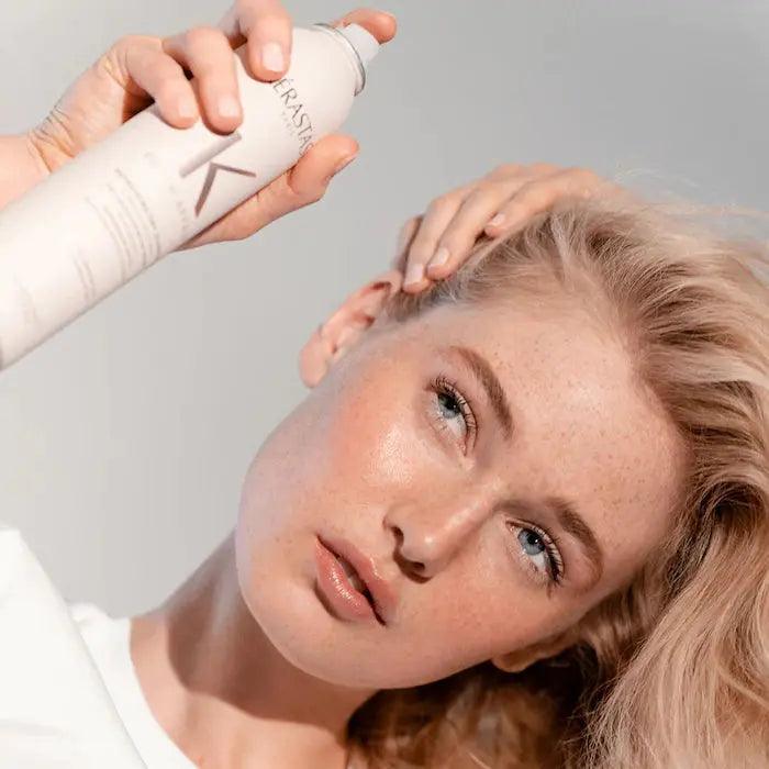 Woman applying Kerastase hair product for healthy, shiny hair