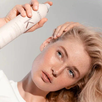 Woman applying Kerastase hair product for healthy, shiny hair