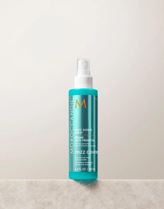 Moroccanoil Frizz Shield Spray bottle on a light background, designed for humidity resistance and frizz control.