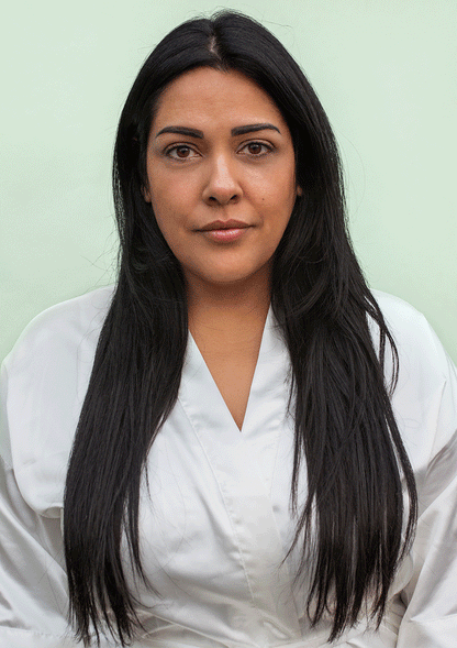 Woman with long, straight dark hair wearing a white robe against a light green background.