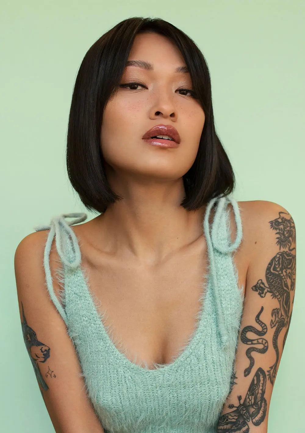 Model showcasing a mint green fluffy sweater with a trendy bob hairstyle against a pastel green background.