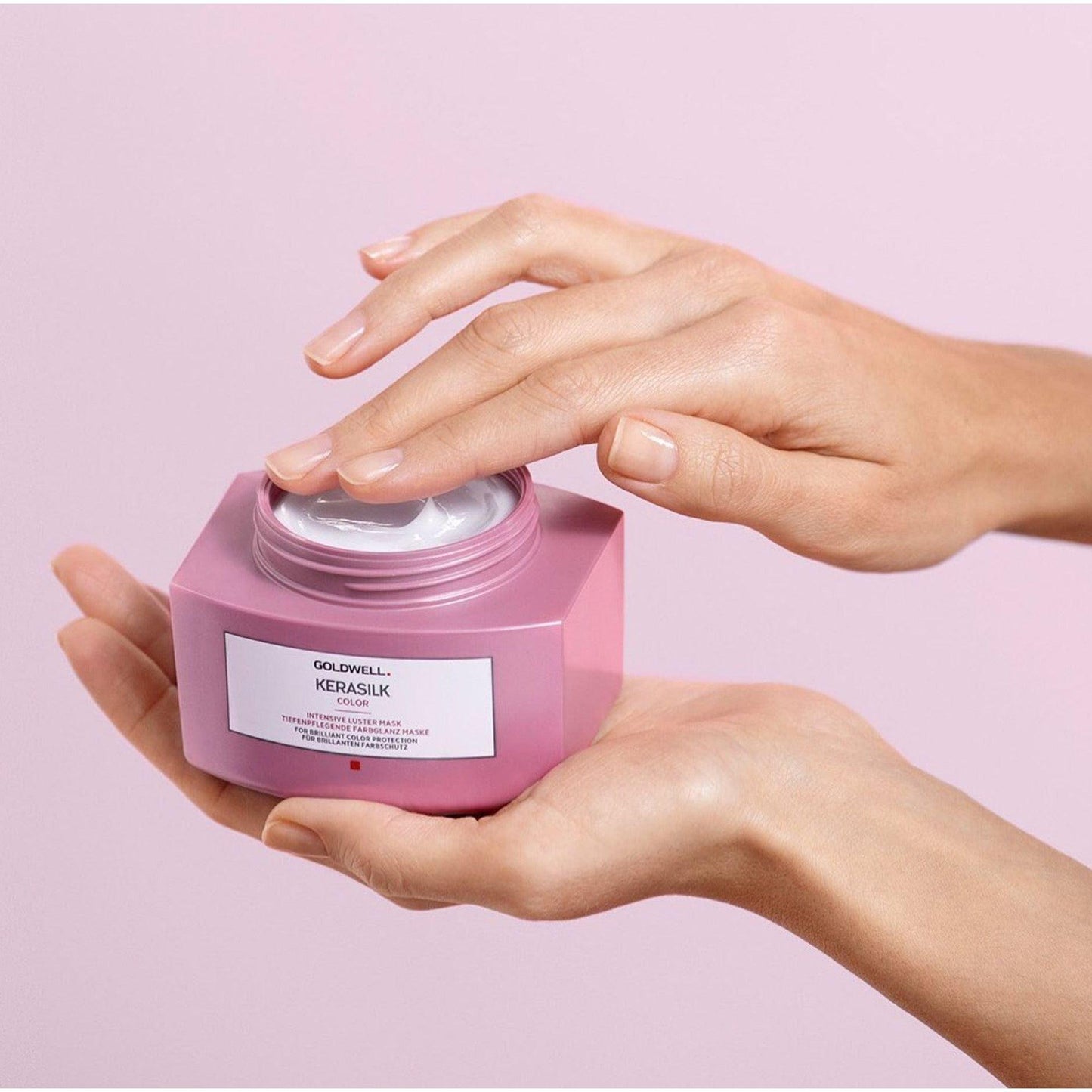 A person holding Goldwell Kerasilk Color Intensive Luster Mask, a nourishing hair treatment for dry, damaged hair.