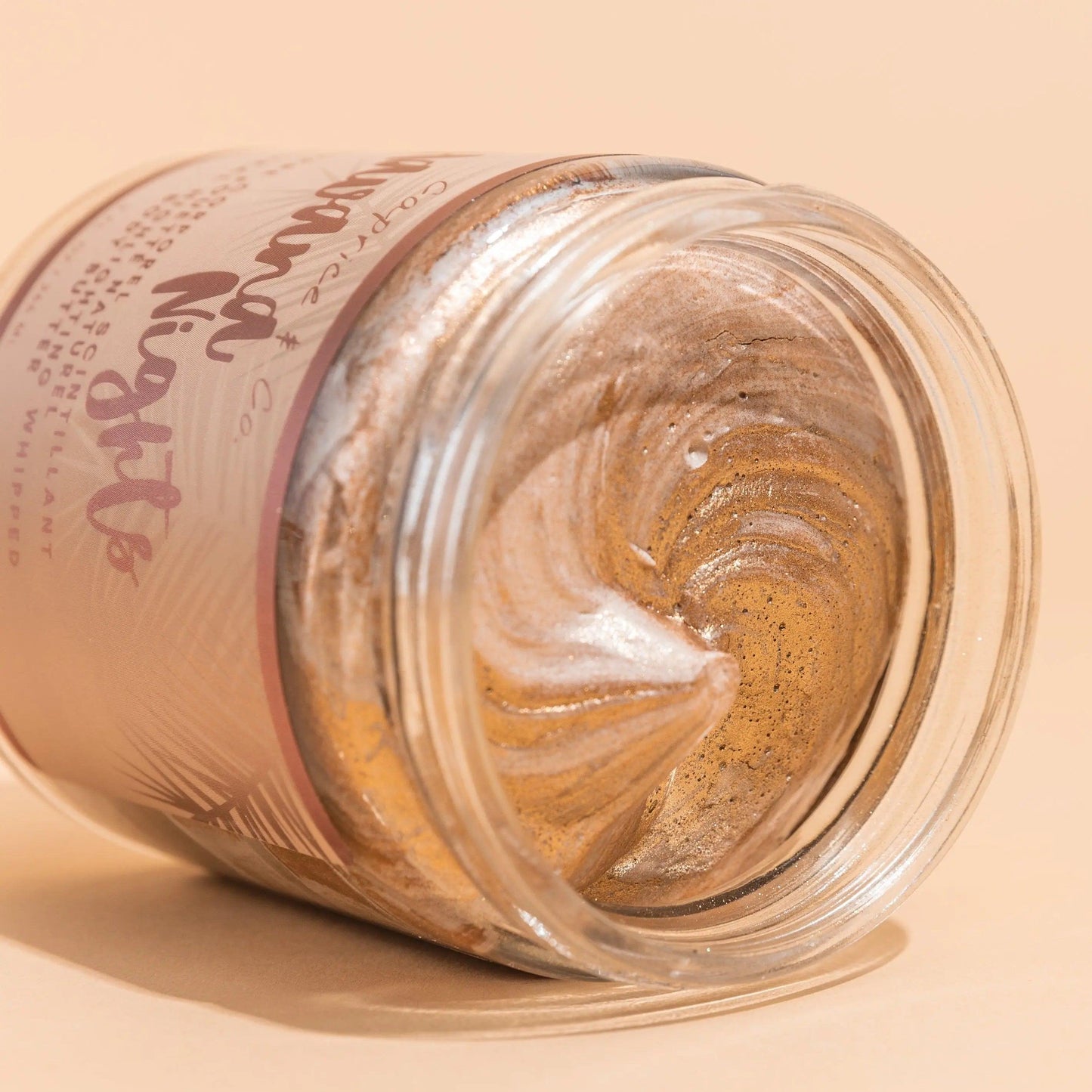 Shimmering bronze body butter in jar, showcasing creamy texture and luxurious golden swirls. Perfect for summer glow.