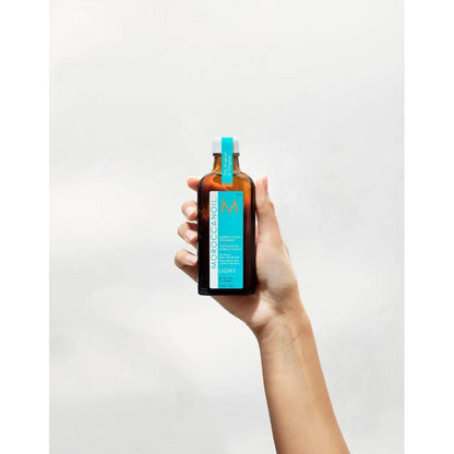 Hand holding a bottle of Moroccanoil Light Treatment for fine hair, infused with argan oil for softness and shine.