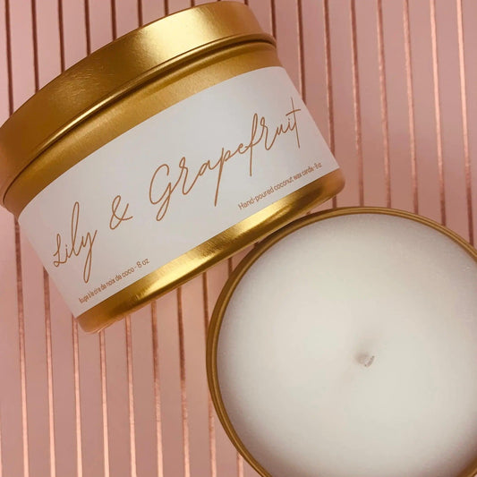 Gold metal tin candle labeled Lily & Grapefruit, showcasing scented coconut wax blend and essential oils.
