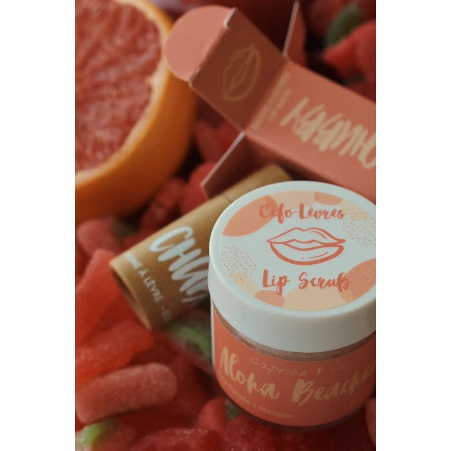 Aloha Beaches Lip Scrub with Pina Colada and Mango flavor surrounded by vibrant fruit and candy elements.
