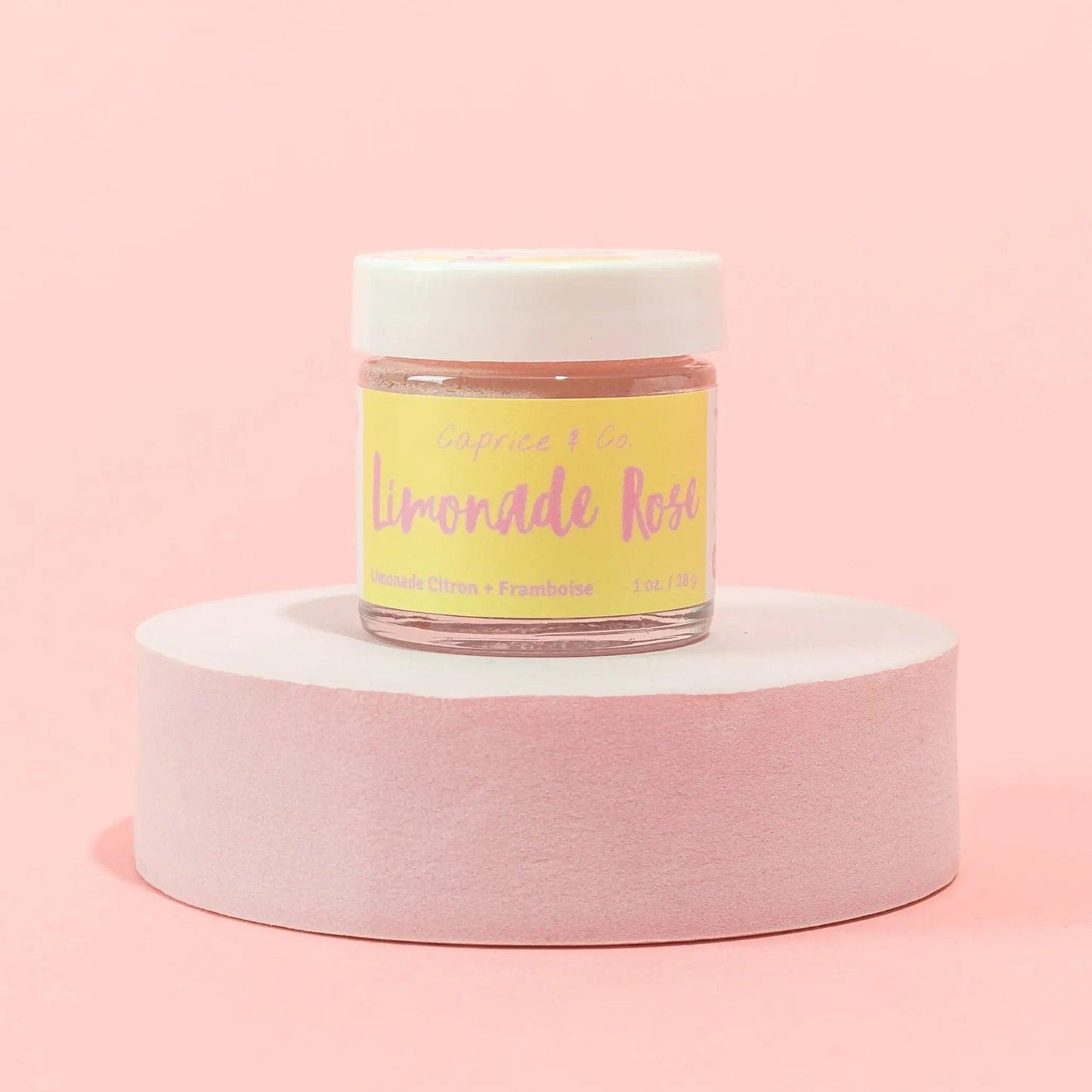 Lip Scrub Limonade Rose in jar on pink background, featuring lemonade citrus and raspberry flavors for soft, smooth lips.
