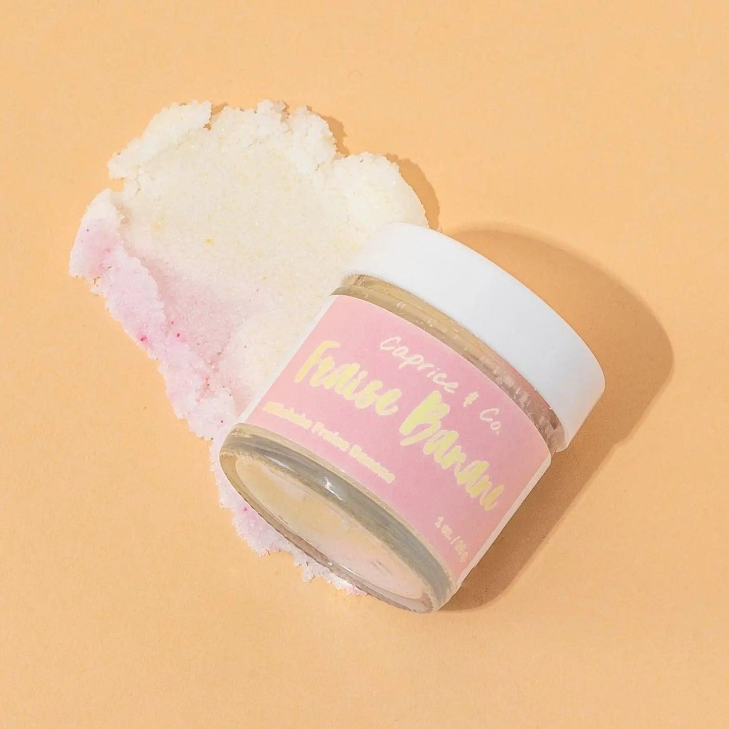 Strawberry banana lip scrub jar with exfoliating sugar scrub on a peach background. Perfect for smooth, soft lips.