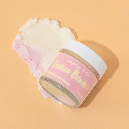 Strawberry banana lip scrub jar with exfoliating sugar scrub on a peach background. Perfect for smooth, soft lips.