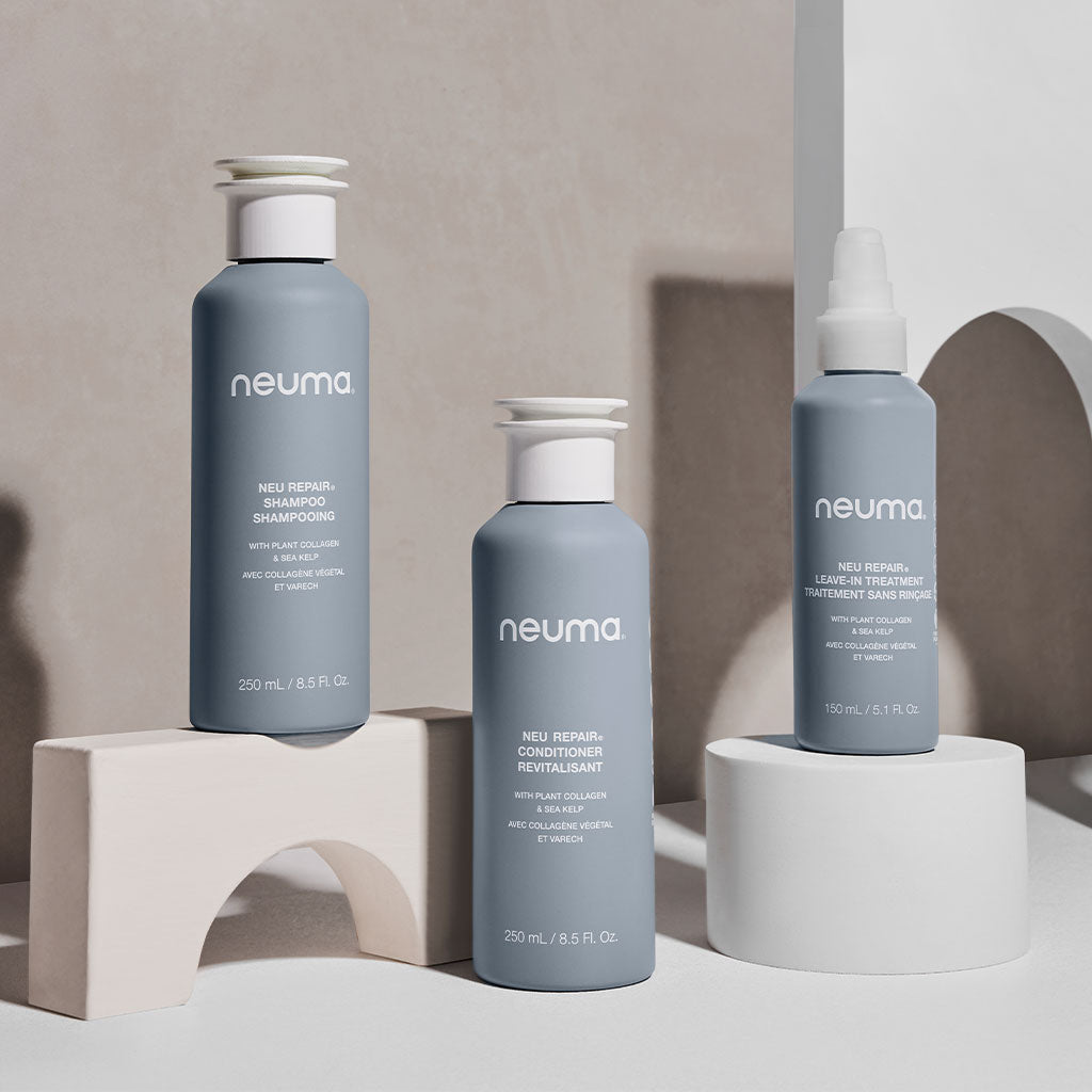 Neuma Neu Repair Shampoo, Conditioner, and Treatment bottles on display, featuring a modern design.